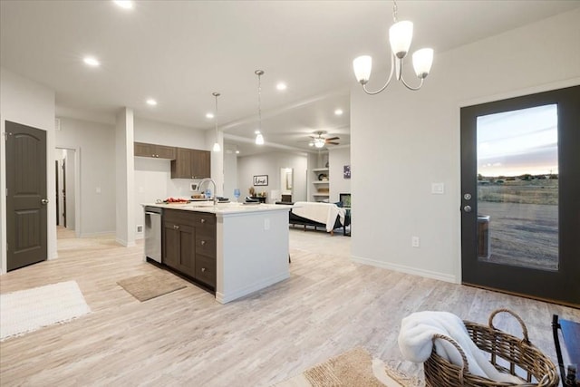 kitchen with a center island with sink, light countertops, hanging light fixtures, light wood-style floors, and open floor plan