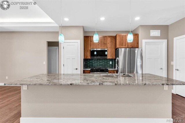 3010 Grandview Ave, Canon City, CO 81212 - kitchen with stainless steel appliances, backsplash, wood finished floors, brown cabinets, and hanging light fixtures