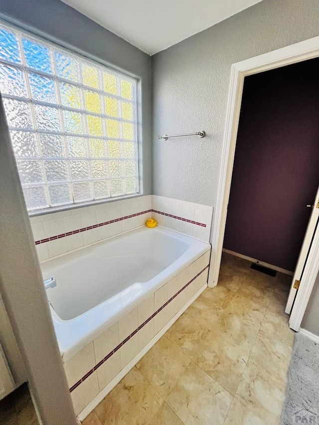 bathroom with a garden tub and a textured wall