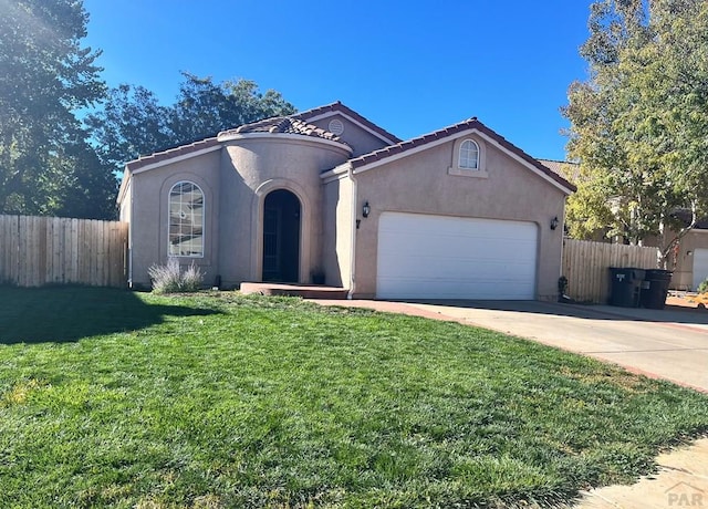 mediterranean / spanish-style house with a garage, fence, concrete driveway, a tiled roof, and stucco siding