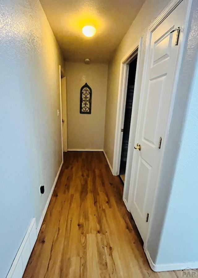 hall featuring a baseboard heating unit, wood finished floors, and baseboards