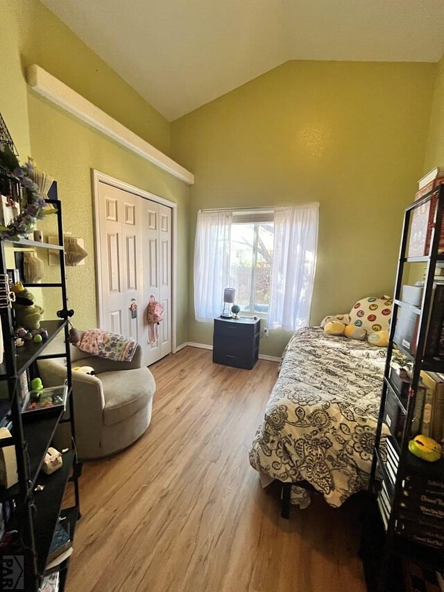 bedroom featuring lofted ceiling, a closet, baseboards, and wood finished floors