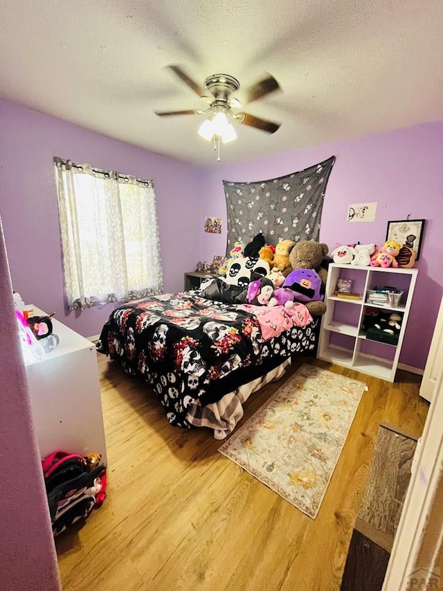 bedroom with a textured ceiling, ceiling fan, and wood finished floors