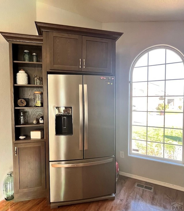 kitchen with dark brown cabinetry, wood finished floors, visible vents, stainless steel refrigerator with ice dispenser, and open shelves