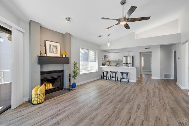 3666 Iguana Dr, Colorado Springs, CO 80910 - living room featuring a fireplace with flush hearth, a ceiling fan, lofted ceiling, light wood-style flooring, and baseboards