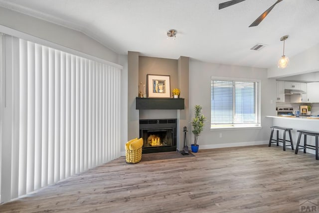 3666 Iguana Dr, Colorado Springs, CO 80910 - living area with a fireplace with flush hearth, wood finished floors, lofted ceiling, ceiling fan, and baseboards
