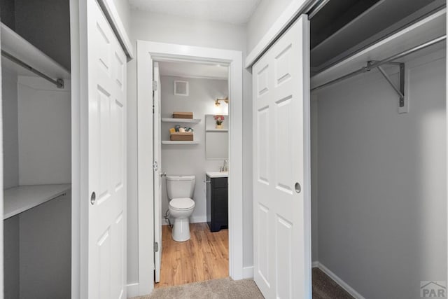 3666 Iguana Dr, Colorado Springs, CO 80910 - bathroom featuring toilet, vanity, a closet, baseboards, and wood finished floors