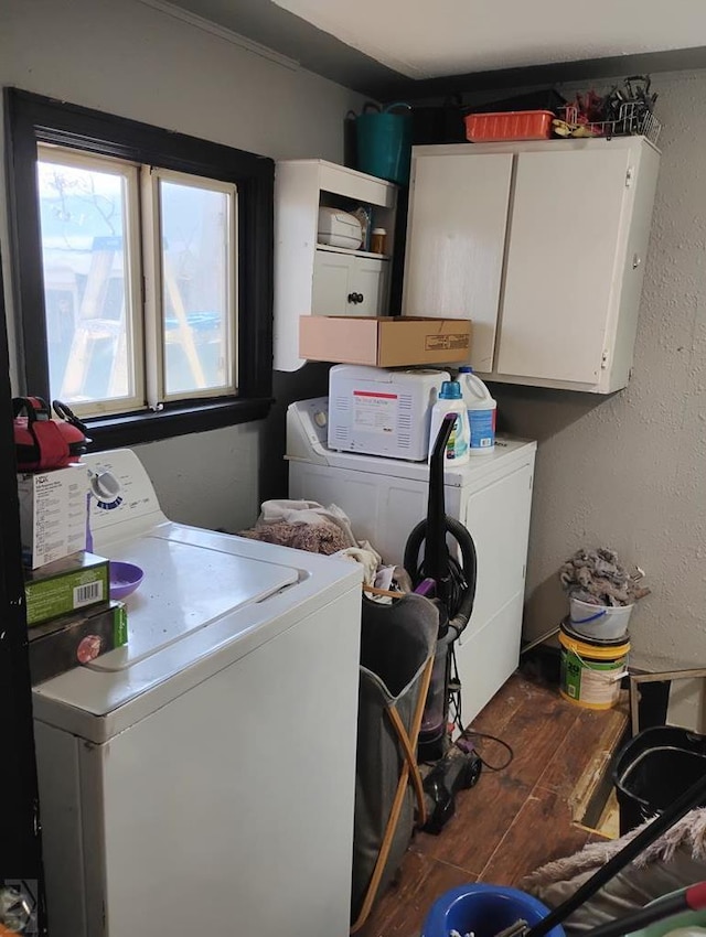 laundry room featuring cabinet space, a textured wall, dark wood-style floors, and washing machine and clothes dryer