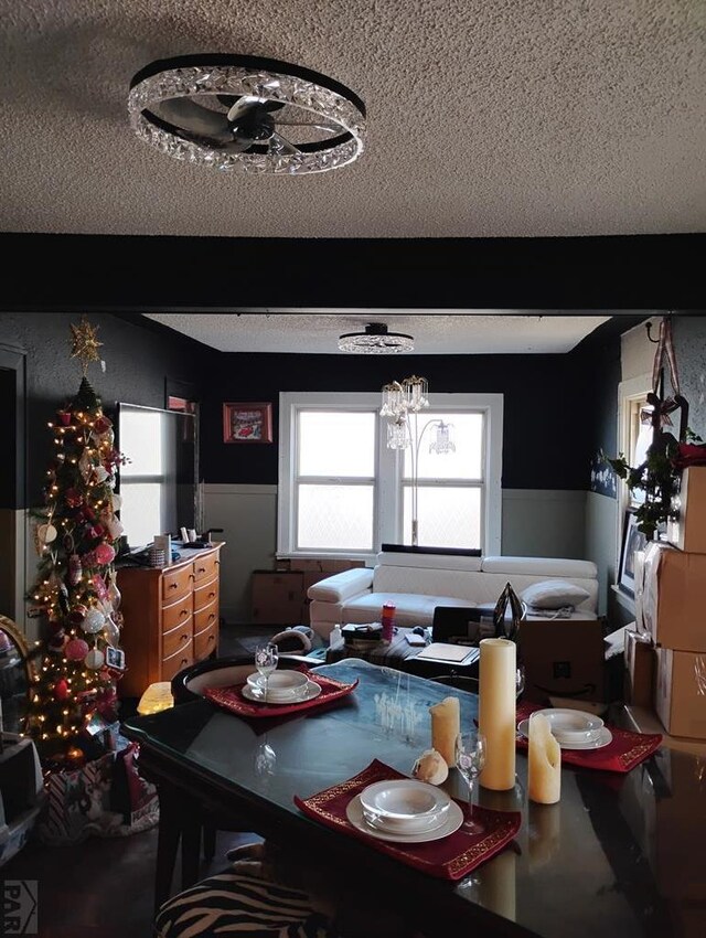 dining space featuring a wainscoted wall, beam ceiling, and a textured ceiling