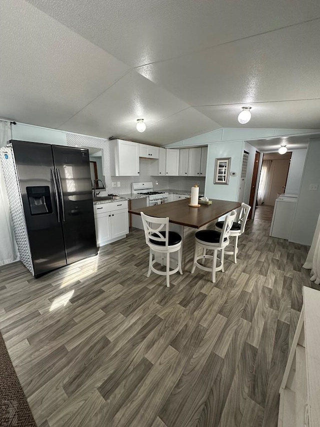 dining area featuring a textured ceiling, dark wood-style floors, and vaulted ceiling