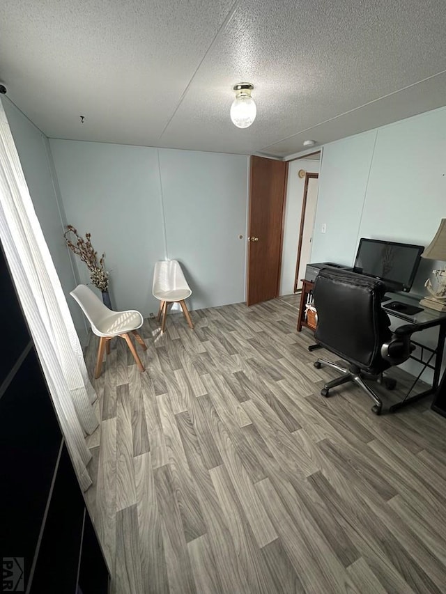 home office with light wood finished floors and a textured ceiling