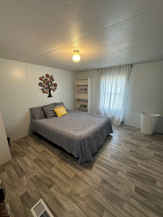 bedroom with a textured ceiling and wood finished floors