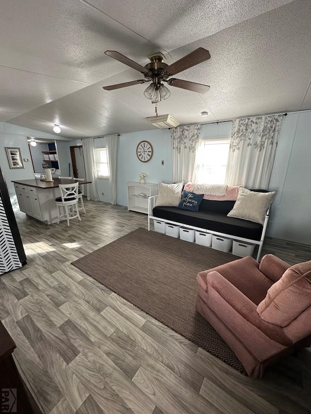 living area featuring ceiling fan, a textured ceiling, and wood finished floors