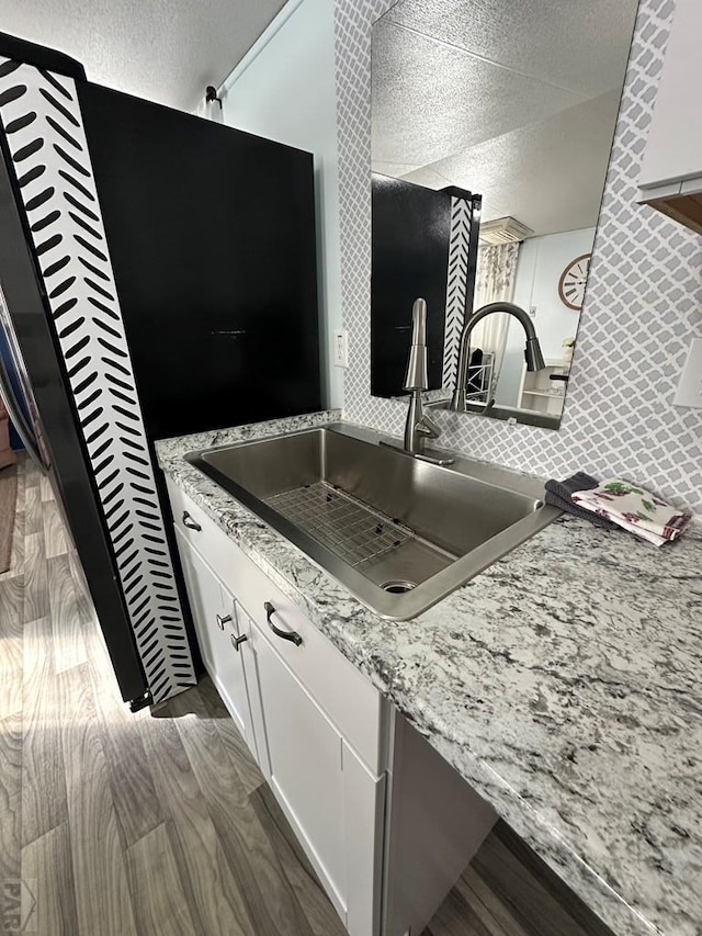 kitchen featuring dark wood-style flooring, a sink, white cabinets, a textured ceiling, and backsplash