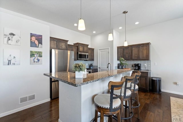 kitchen featuring appliances with stainless steel finishes, visible vents, dark brown cabinets, and baseboards
