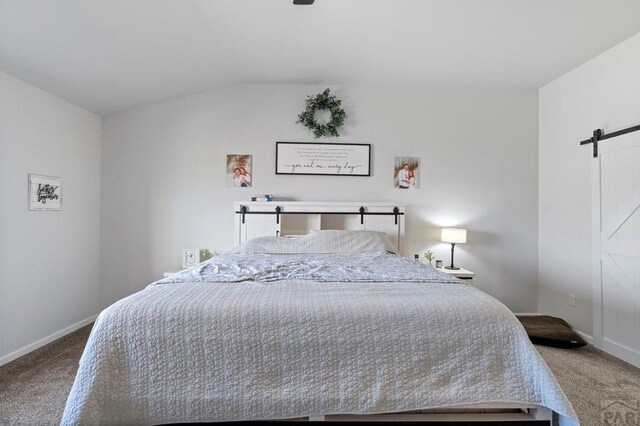 carpeted bedroom with baseboards, a barn door, and vaulted ceiling