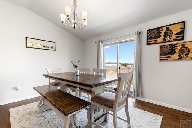 dining space with dark wood-style floors, a notable chandelier, vaulted ceiling, and baseboards