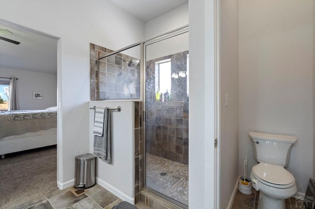 ensuite bathroom featuring toilet, a shower stall, ensuite bath, and baseboards