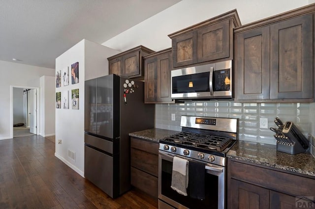 kitchen with dark stone counters, dark brown cabinetry, visible vents, and appliances with stainless steel finishes