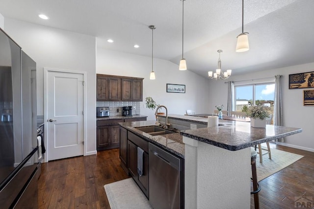kitchen with a kitchen breakfast bar, lofted ceiling, a sink, appliances with stainless steel finishes, and a notable chandelier