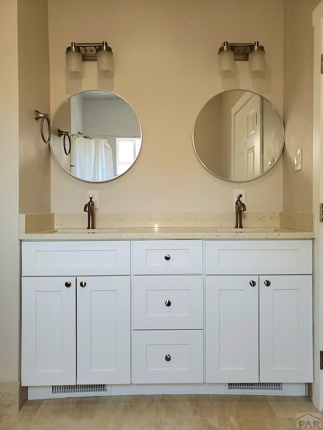 bathroom with double vanity, visible vents, and a sink