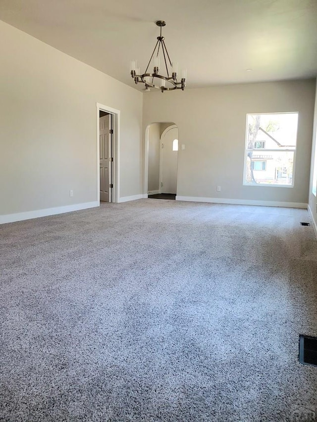 empty room featuring arched walkways, visible vents, an inviting chandelier, baseboards, and speckled floor