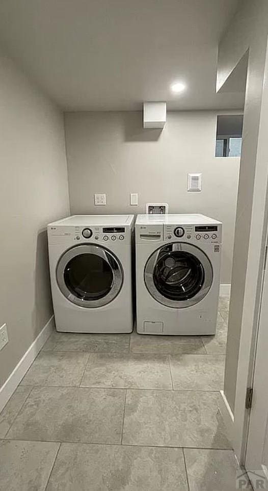 clothes washing area featuring laundry area, baseboards, and washing machine and clothes dryer