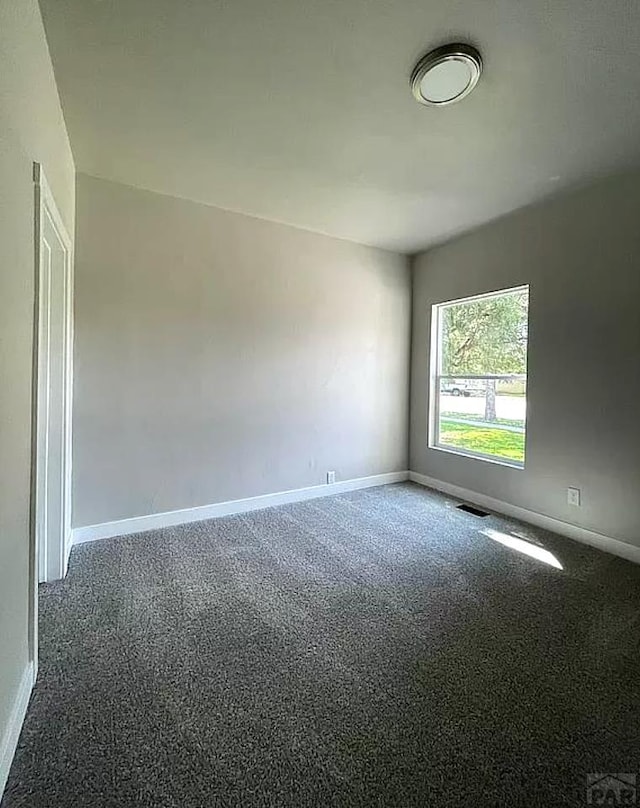 spare room with visible vents, baseboards, and dark carpet