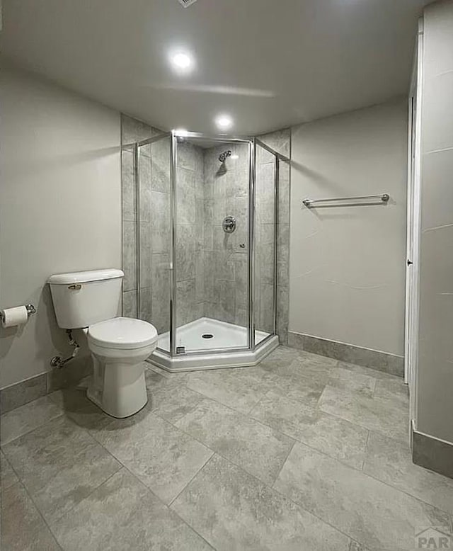 bathroom featuring baseboards, a shower stall, and toilet