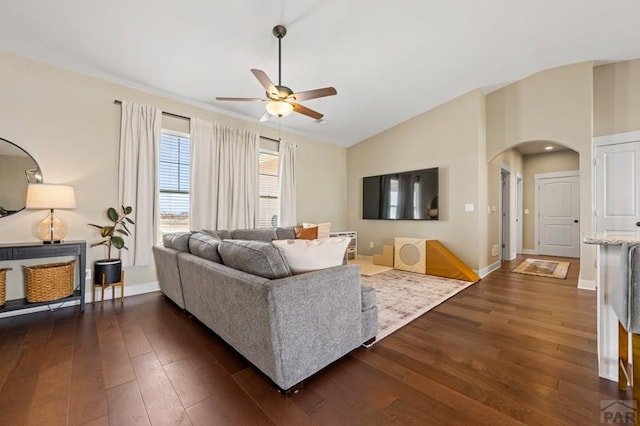 living room featuring ceiling fan, arched walkways, dark wood-type flooring, lofted ceiling, and baseboards