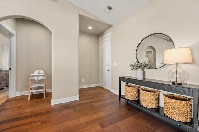 hallway with lofted ceiling, arched walkways, wood finished floors, baseboards, and recessed lighting