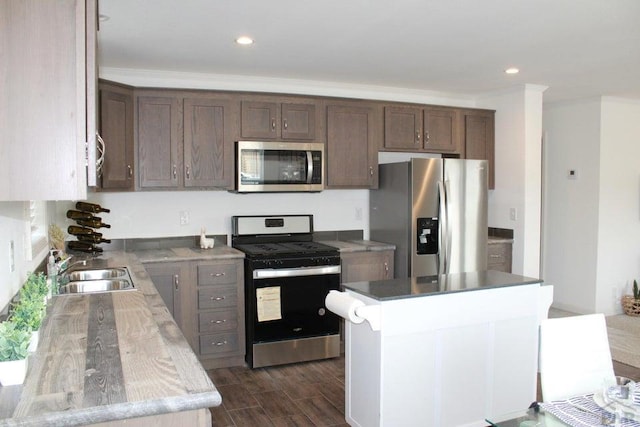 kitchen featuring dark wood finished floors, a kitchen island, appliances with stainless steel finishes, dark brown cabinets, and a sink