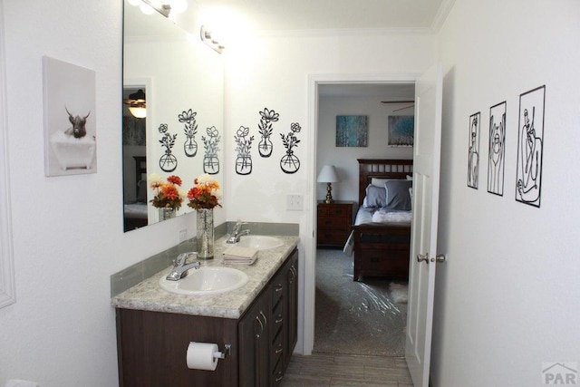 ensuite bathroom with connected bathroom, double vanity, a sink, and ornamental molding