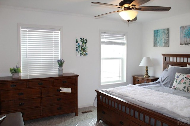 bedroom featuring a ceiling fan, visible vents, and light carpet