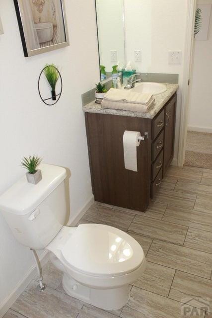 bathroom with toilet, baseboards, and vanity