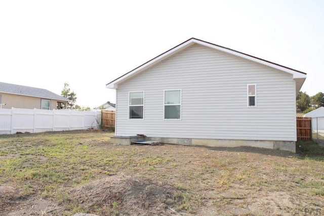 rear view of house with a yard and fence