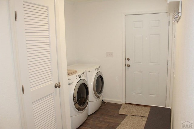 clothes washing area with laundry area, dark wood finished floors, washer and clothes dryer, and baseboards