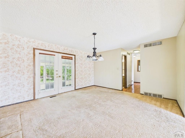 9 Woodsorrel Ct, Pueblo, CO 81001 - spare room with wallpapered walls, carpet flooring, french doors, a textured ceiling, and baseboards