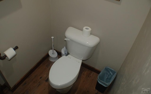 bathroom with toilet, baseboards, and wood finished floors