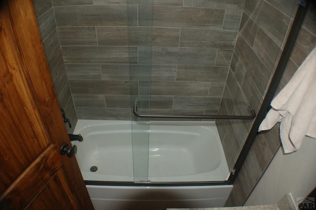 bathroom featuring bath / shower combo with glass door