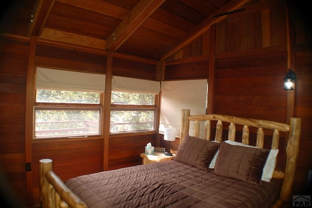 bedroom with multiple windows, wooden walls, wooden ceiling, and vaulted ceiling with beams