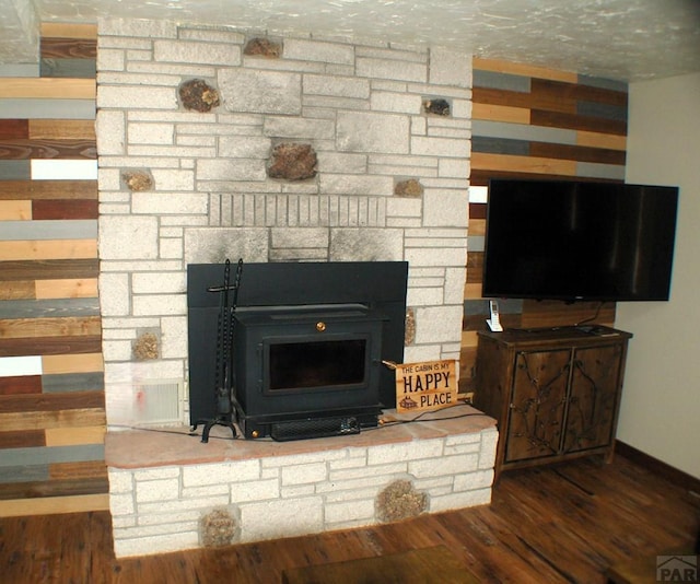 interior details featuring a fireplace, a wood stove, baseboards, and wood finished floors