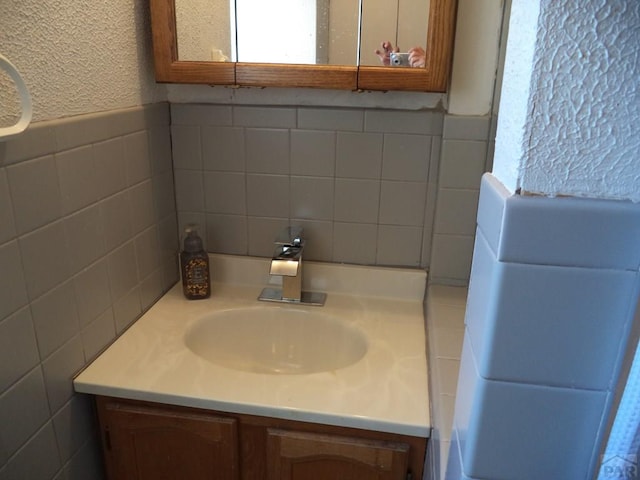 bathroom with vanity, a wainscoted wall, and tile walls