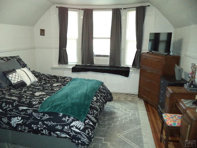 bedroom with cooling unit, wood finished floors, and lofted ceiling