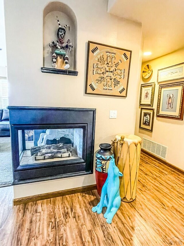 interior details with visible vents, a fireplace, baseboards, and wood finished floors