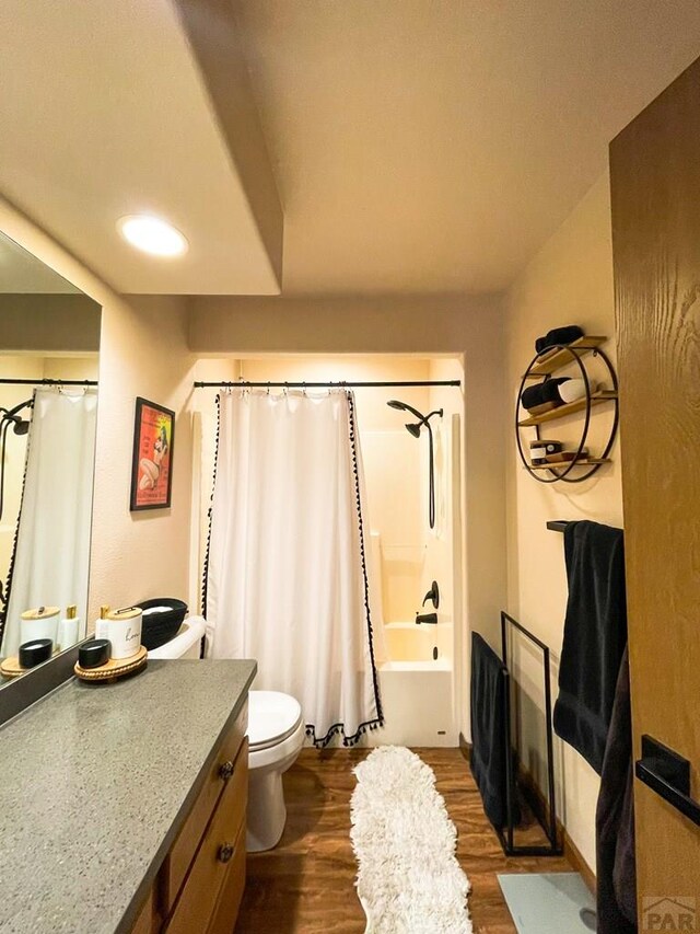 bathroom featuring toilet, shower / bath combo with shower curtain, wood finished floors, and vanity