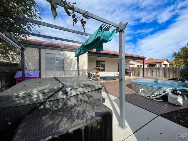 view of patio / terrace featuring a deck, fence, an outdoor living space, and a hot tub