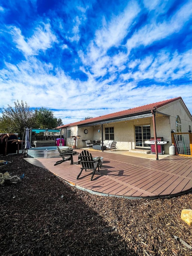 back of house with a wooden deck, a patio, and stucco siding