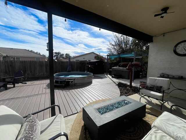 wooden terrace featuring a fenced backyard, an outdoor hot tub, and an outdoor living space with a fire pit