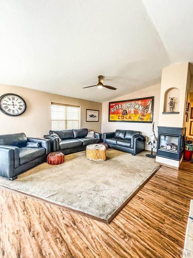 living room featuring lofted ceiling, ceiling fan, a multi sided fireplace, and wood finished floors